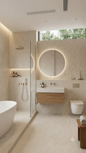 Load image into Gallery viewer, Modern minimalist bathroom interior with a freestanding bathtub, glass shower enclosure, wall-mounted sink with wood vanity, round backlit mirror, toilet, and light stone surfaces.