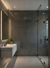 Load image into Gallery viewer, Modern bathroom interior with a large dark gray marble-look wall, a floating white vanity with a sink, a glass shower enclosure, and warm recessed lighting.

