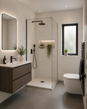 Load image into Gallery viewer, Modern bathroom interior with a walk-in shower enclosure, floating vanity, toilet, window, and small plants. 
