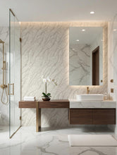 Load image into Gallery viewer, Modern bathroom vanity with a large rectangular mirror, white marble countertop and backsplash, floating dark wood cabinet, and a glass shower enclosure.

